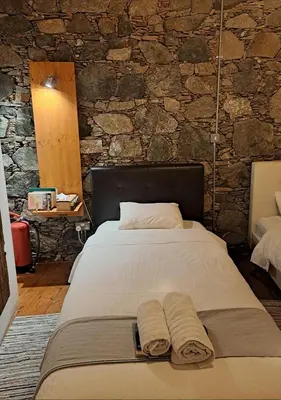 a bed in a room with a stone wall at To Apokentro in Alona