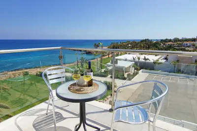 a table with two chairs and wine glasses on a balcony at Apartment Erika in Protaras