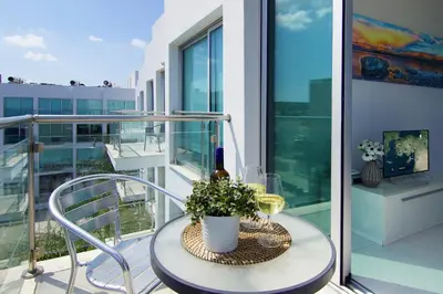 a table with a bottle of wine and a plant on a balcony at Apartment Erika in Protaras