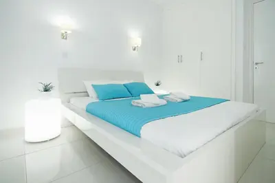 a white bedroom with a bed with blue pillows at Apartment Erika in Protaras