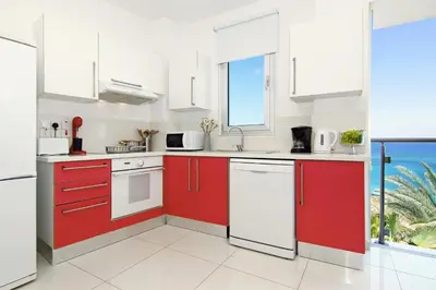 a kitchen with red cabinets and a view of the ocean at Apartment Erika in Protaras