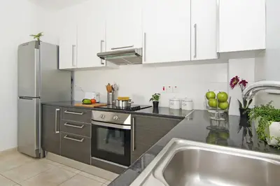 a kitchen with white cabinets and a stainless steel refrigerator at Amber - Coralli Beachfront Apartment in Protaras