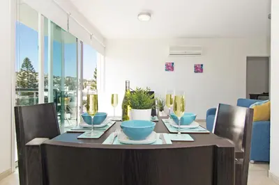 a dining room table with blue bowls and plates on it at Amber - Coralli Beachfront Apartment in Protaras