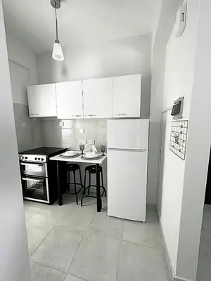 a kitchen with a white refrigerator and a table at Engomi Apartment in Yukarı Lakatamya