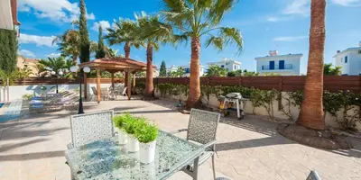 a patio with a table and chairs and palm trees at Villa Stefanie in Ayia Napa