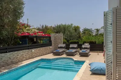 a swimming pool with chaise lounge chairs next to a swimming pool at Villa Mesogeios 39 in Paralimni