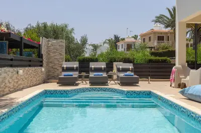 a swimming pool with chaise lounge chairs and a patio with a swimming pool at Villa Mesogeios 39 in Paralimni