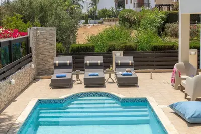 a swimming pool with lounge chairs and a table and a swimming pool at Villa Mesogeios 39 in Paralimni