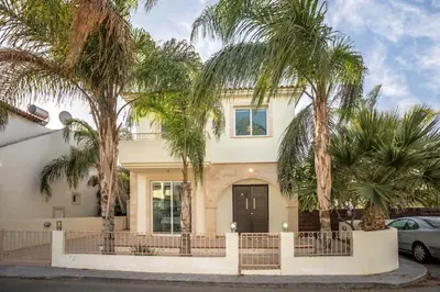 a house with palm trees in front of it at Villa Costas in Protaras