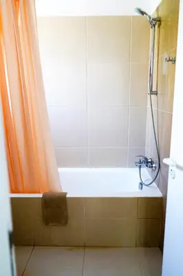 a bathroom with a bathtub with an orange shower curtain at Green Bungalows Hotel Apartments in Ayia Napa