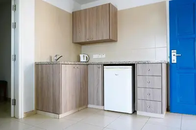 a kitchen with wooden cabinets and a refrigerator at Green Bungalows Hotel Apartments in Ayia Napa