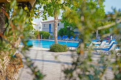 a swimming pool with blue chairs and a resort at Green Bungalows Hotel Apartments in Ayia Napa