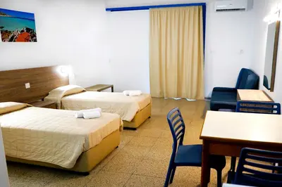 a hotel room with two beds and a table and chairs at Green Bungalows Hotel Apartments in Ayia Napa