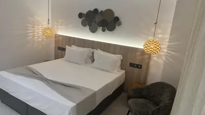 a bedroom with a bed with a chair and two lights at Abacus Suites in Ayia Napa