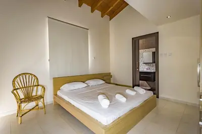 a bedroom with a bed with white sheets and a chair at Marina Estate in Protaras