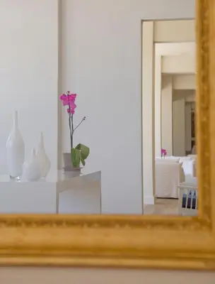a mirror with a vase with a flower on a shelf at Sandy Beach Hotel & Spa - ex Sentido in Larnaka