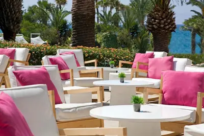 a row of tables and chairs with pink cushions at Sandy Beach Hotel & Spa - ex Sentido in Larnaka