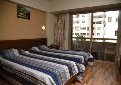 two beds in a hotel room with a balcony at Elysso Hotel in Larnaka