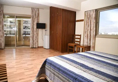 a bedroom with a bed and a sliding glass door at Elysso Hotel in Larnaka