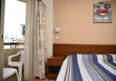a bedroom with a bed and a desk and a window at Elysso Hotel in Larnaka