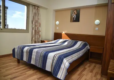 a bedroom with a bed with a striped blanket at Elysso Hotel in Larnaka