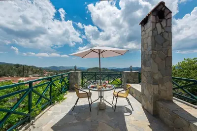 a table and chairs with an umbrella on a balcony at Themis House in Lemithou