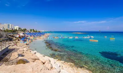 a beach with umbrellas and people in the water at Sunrise Bay Villa #1 in Paralimni