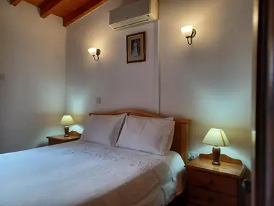 a bedroom with a bed with two lamps and two tables at Niovi House in Tochni