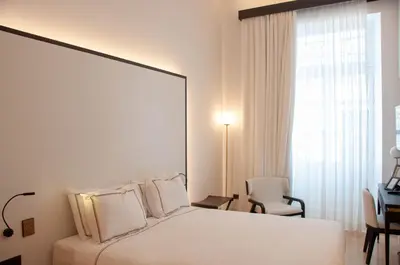 a white bedroom with a bed and a desk and a chair at S Paul City Hotel in Limassol