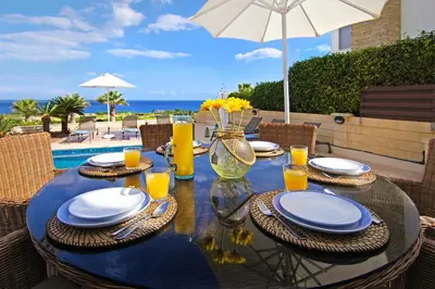 a table with plates and glasses on a table with an umbrella at Villa Venus in Protaras