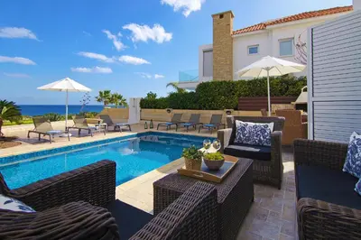a patio with a swimming pool with chairs and a table at Villa Venus in Protaras