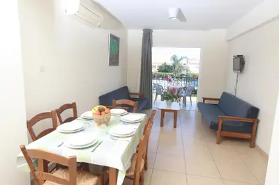 a dining room with a table and chairs and a living room at Captain Karas Holidays Apartments in Protaras