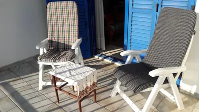 two chairs and a stool sitting on a porch at Rita SeaView Apartment in Pervolia
