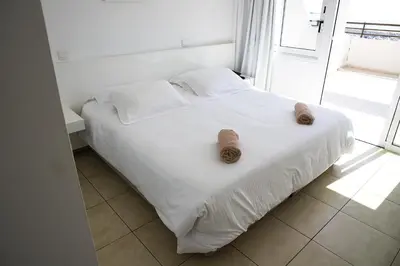 a white bed in a room with a window at Sun Hall Beach Hotel Apartments in Larnaka