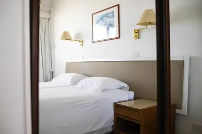 a bedroom with a bed with white sheets and a mirror at Sun Hall Beach Hotel Apartments in Larnaka