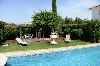 a pool with a fountain and a table and chairs at Karythia in Pyla