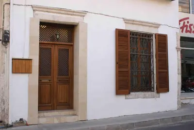 a building with a wooden door and two windows at Yiayia's House Limassol city in Limassol