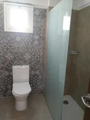 a bathroom with a toilet and a window and a shower at Livas Hotel Apartments in Protaras