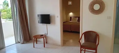 a room with a tv and a chair and a bed at Mandalena Hotel Apartments in Protaras