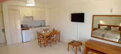 a kitchen with a small table and a kitchen with a bed at Mandalena Hotel Apartments in Protaras