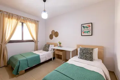 two beds in a room with a desk and a window at Tranquil Kyklades BC6, WALK to BEACH in Paralimni