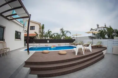 a patio with a pool and chairs and a table at Villa Elena in Ayia Napa