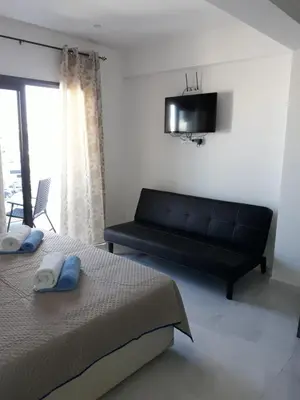 a bedroom with two beds and a black couch at P.L Hermes Studios & Apartments in Larnaka