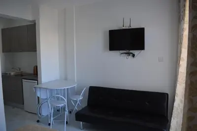 a living room with a couch and a tv on the wall at P.L Hermes Studios & Apartments in Larnaka