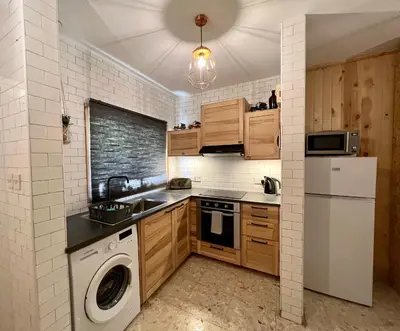 a kitchen with wooden cabinets and a washer and dryer at FatCow Beach House 43 in Larnaka