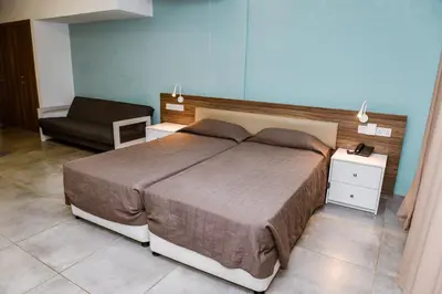 a bedroom with a large bed and a chair at Sweet Memories Hotel Apts in Protaras