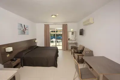 a hotel room with a bed and a table and chairs at Petrosana Hotel Apartments in Ayia Napa