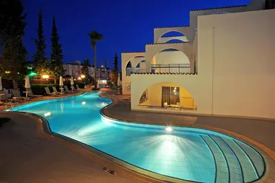 a swimming pool in front of a building at night at Petrosana Hotel Apartments in Ayia Napa