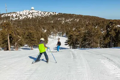 two people are skiing down a snow covered slope at Troodos Hotel & Spa in Troodos