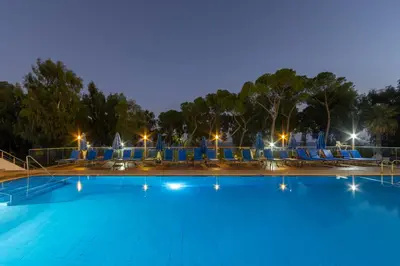 a large swimming pool with blue chairs and lights at Park Beach Hotel in Limassol